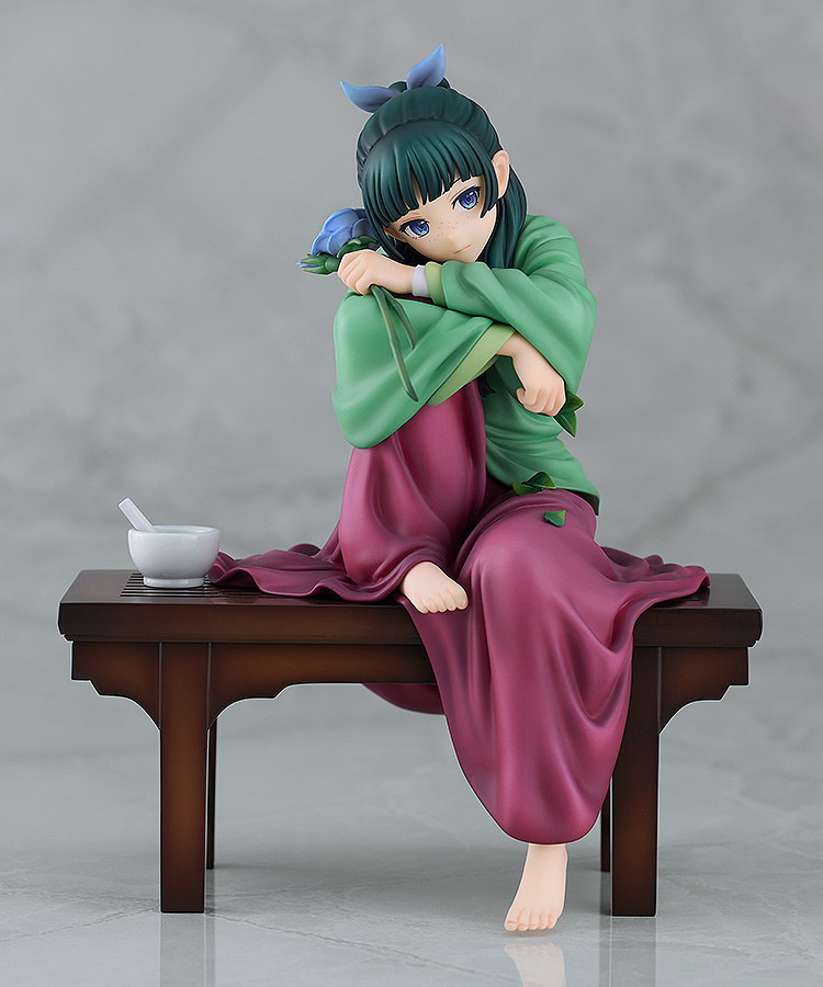 The Maomao figure on its wooden bench photographed against a pale grey marble background, with the white mortar at the end of the bench