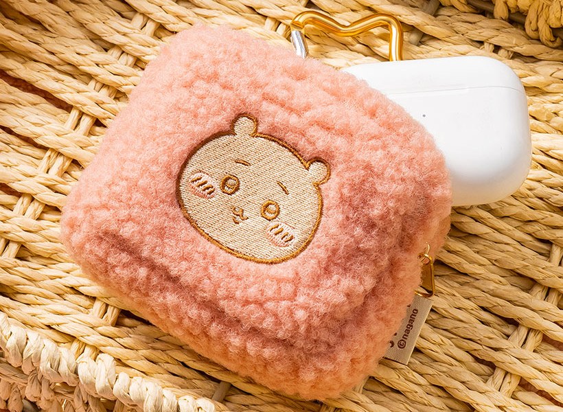 Detail of the embroidered Chiikawa face and curly fluffy texture on the pink carabiner pouch