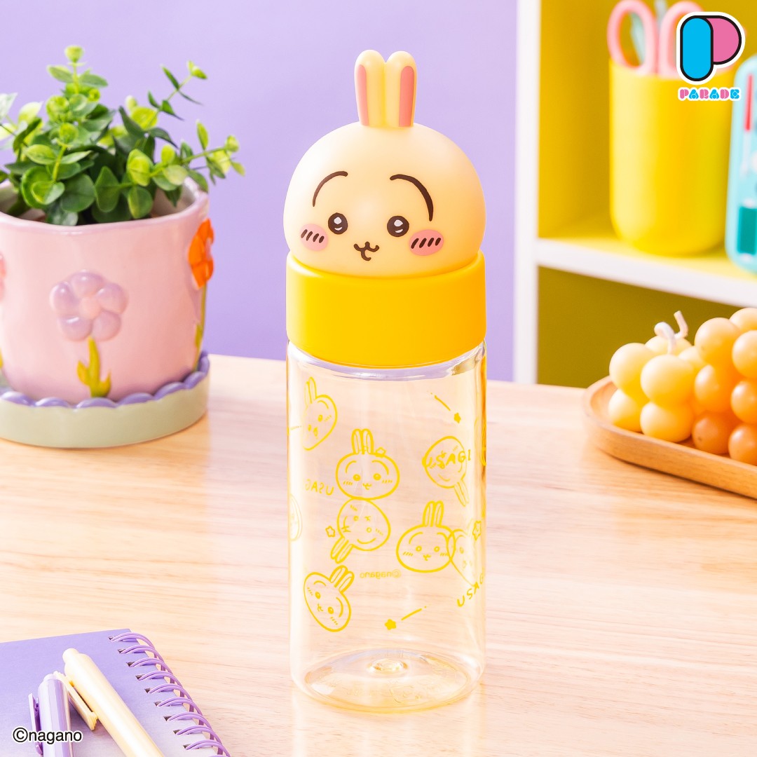 Usagi face bottle with a cream-coloured Usagi head as the lid, a yellow band and yellow Usagi doodles printed on the clear bottle, on a wooden desk