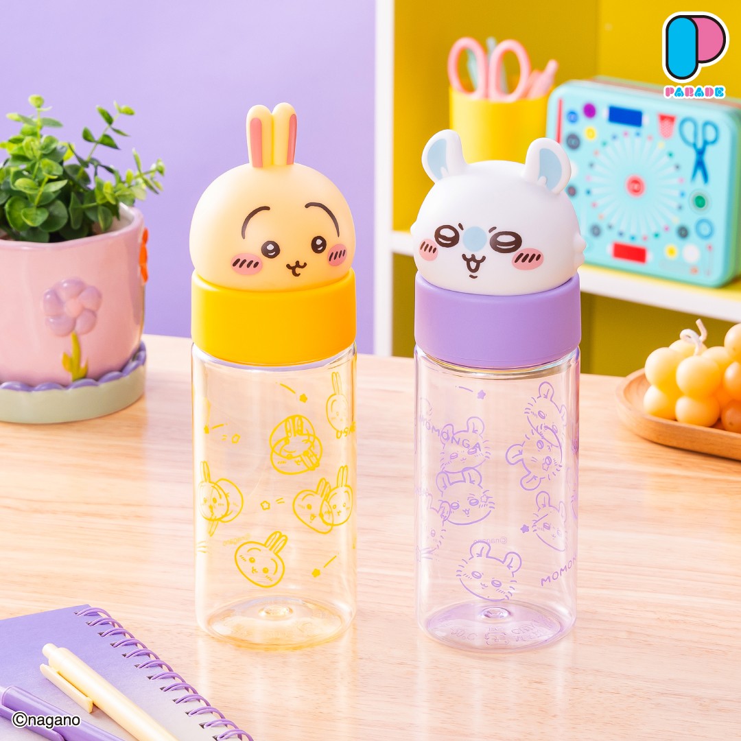 The Usagi and Momonga face bottles side by side on a wooden desk with a potted plant and a craft box in the background