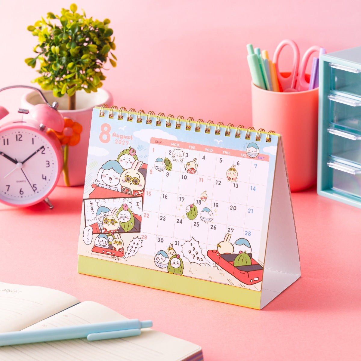 Chiikawa January 2027 desk calendar standing on a pink desk next to flowers and pens