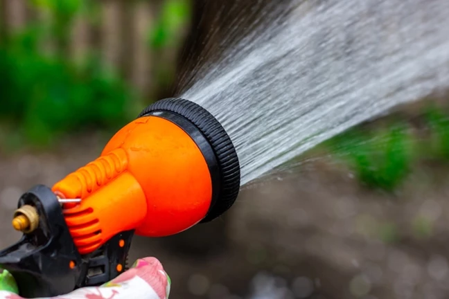 person using a spray gun and spraying water on setting shower