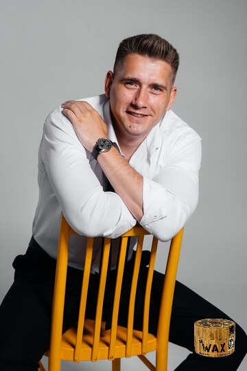 Charismatic Executive posing on a yellow chair with stylish hairstyle crafted by Da'Wax
