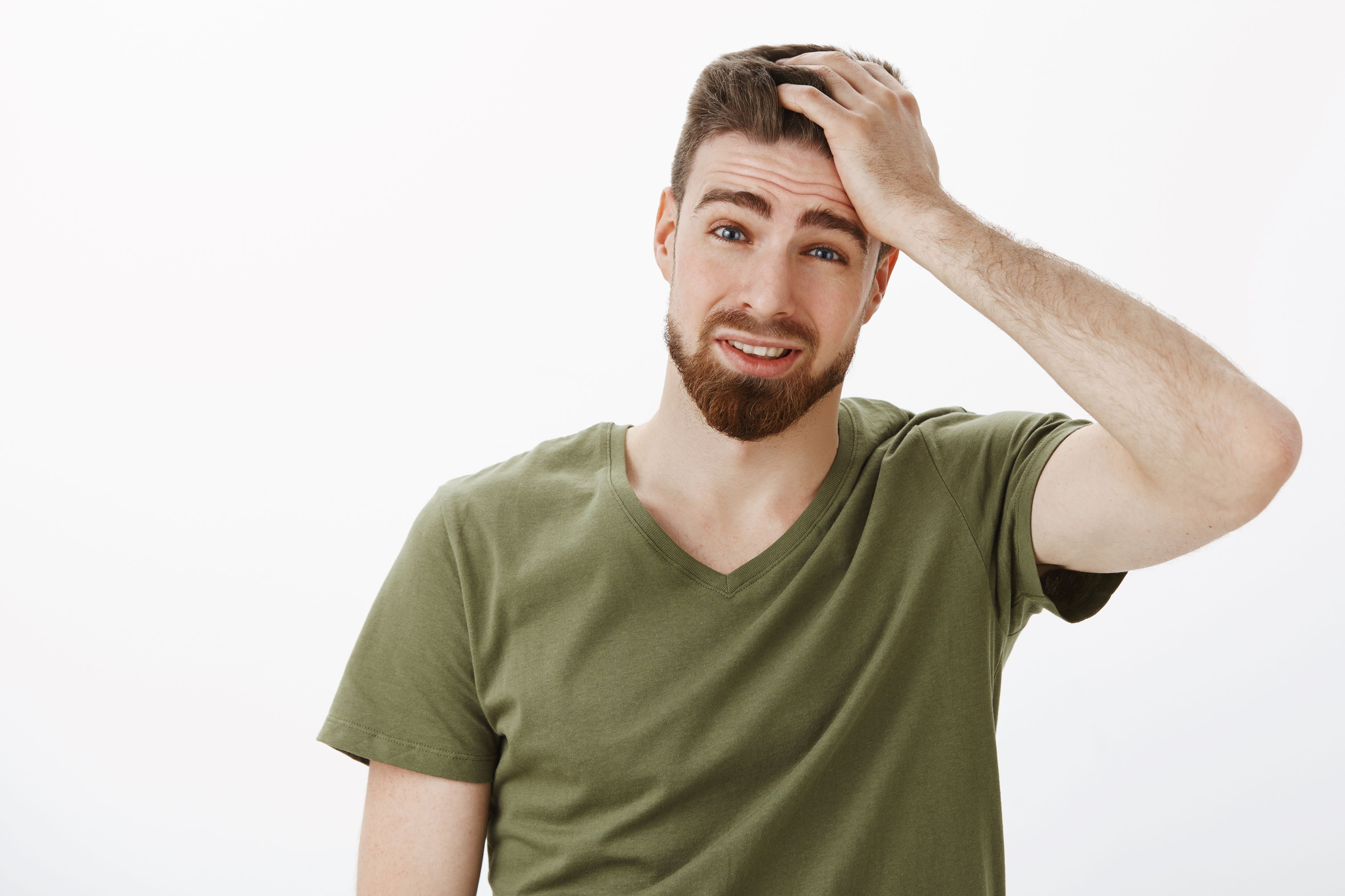 Bearded man in green tee-shirt unhappy with bad hairstyle