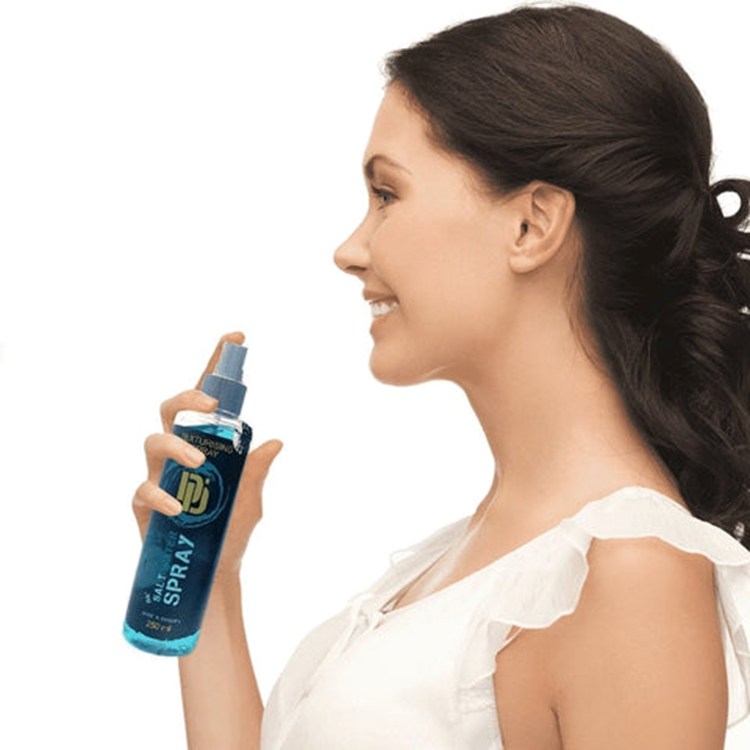 Smiling young woman with thick wavy hair applying Da'Dude Da'Salt Water Spray