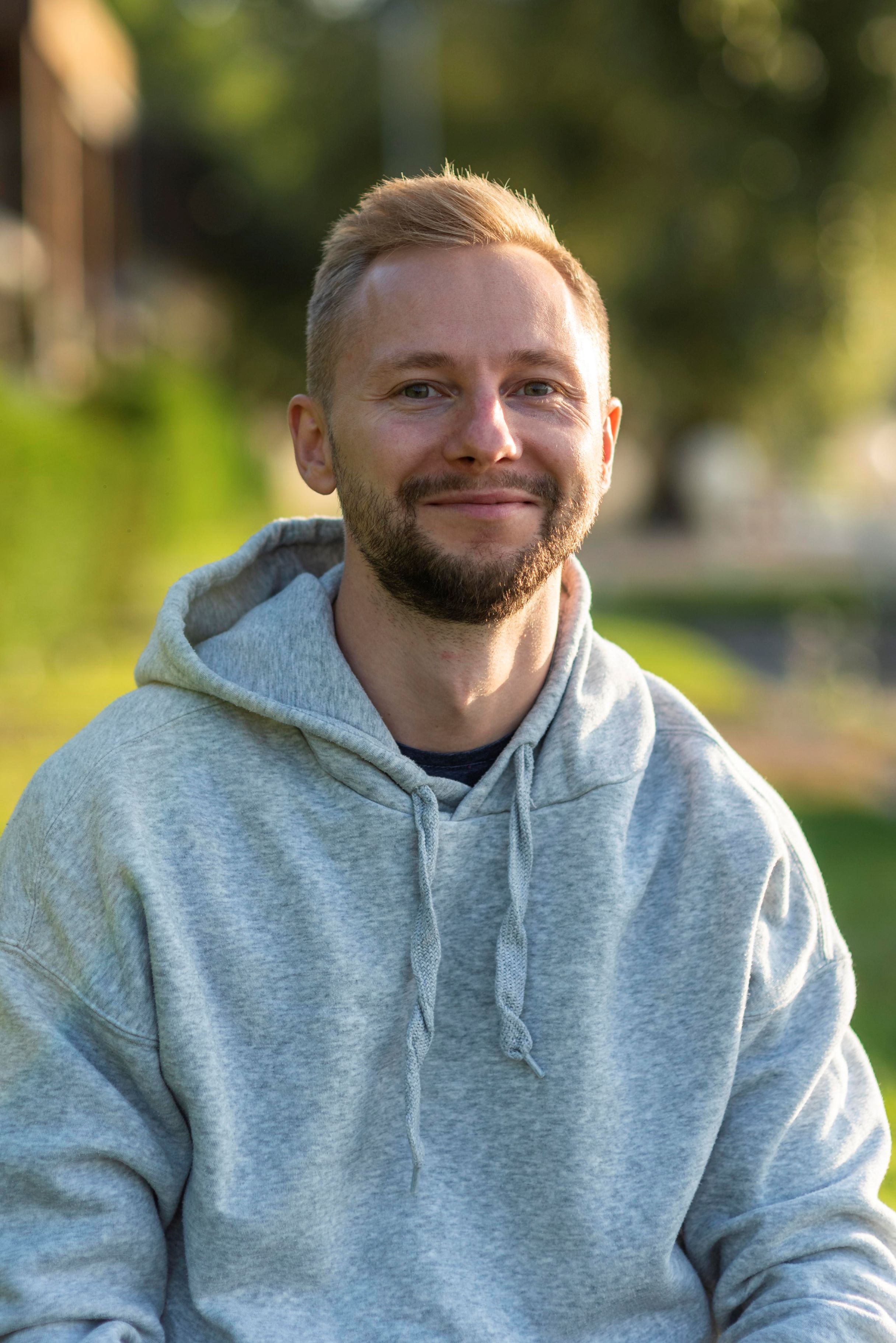 smiling man with round face relaxing outdoors showing natural features