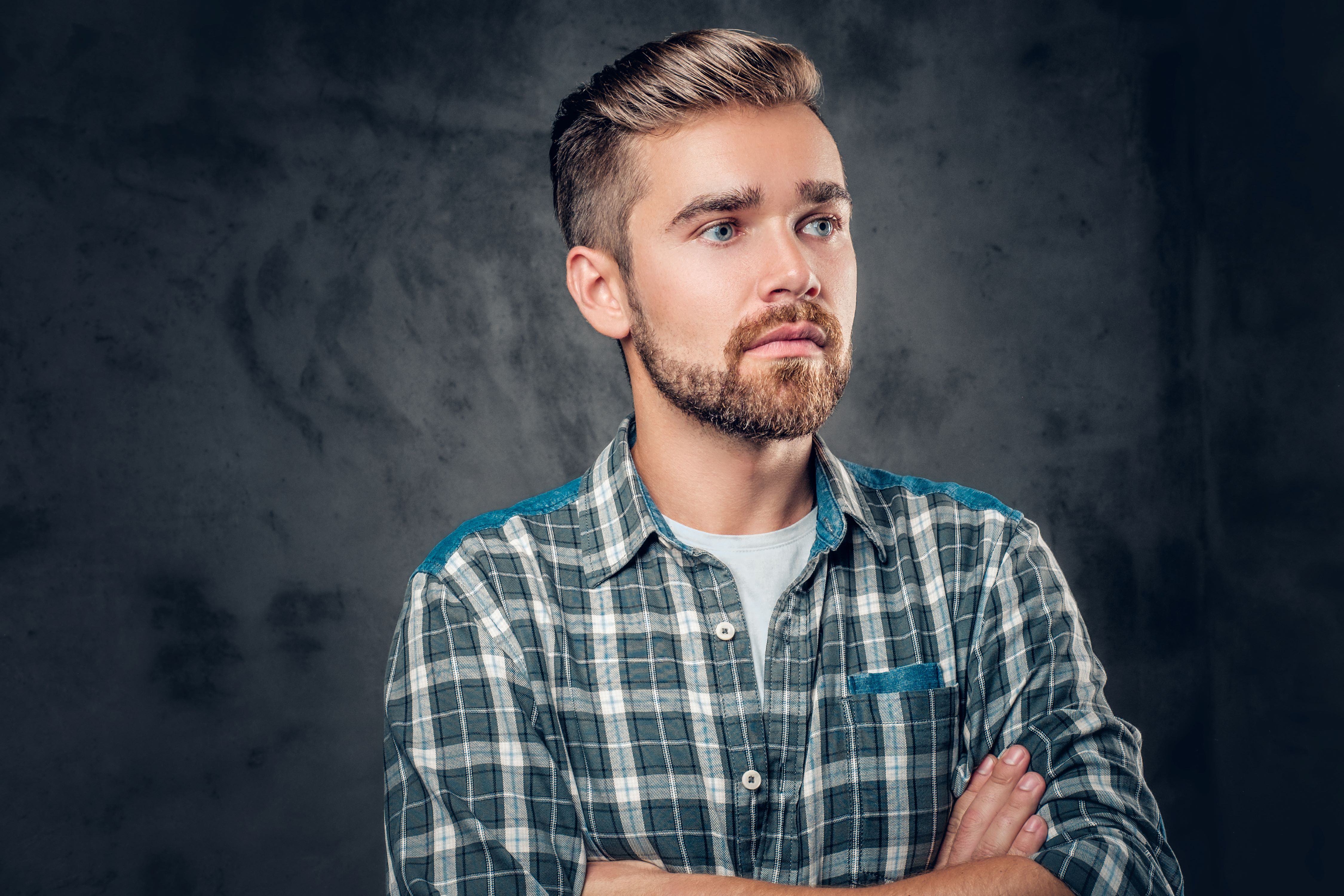 Handsome man in checked shirt against grey background, rocking trendy hairstyle crafted with Da'Wax for men