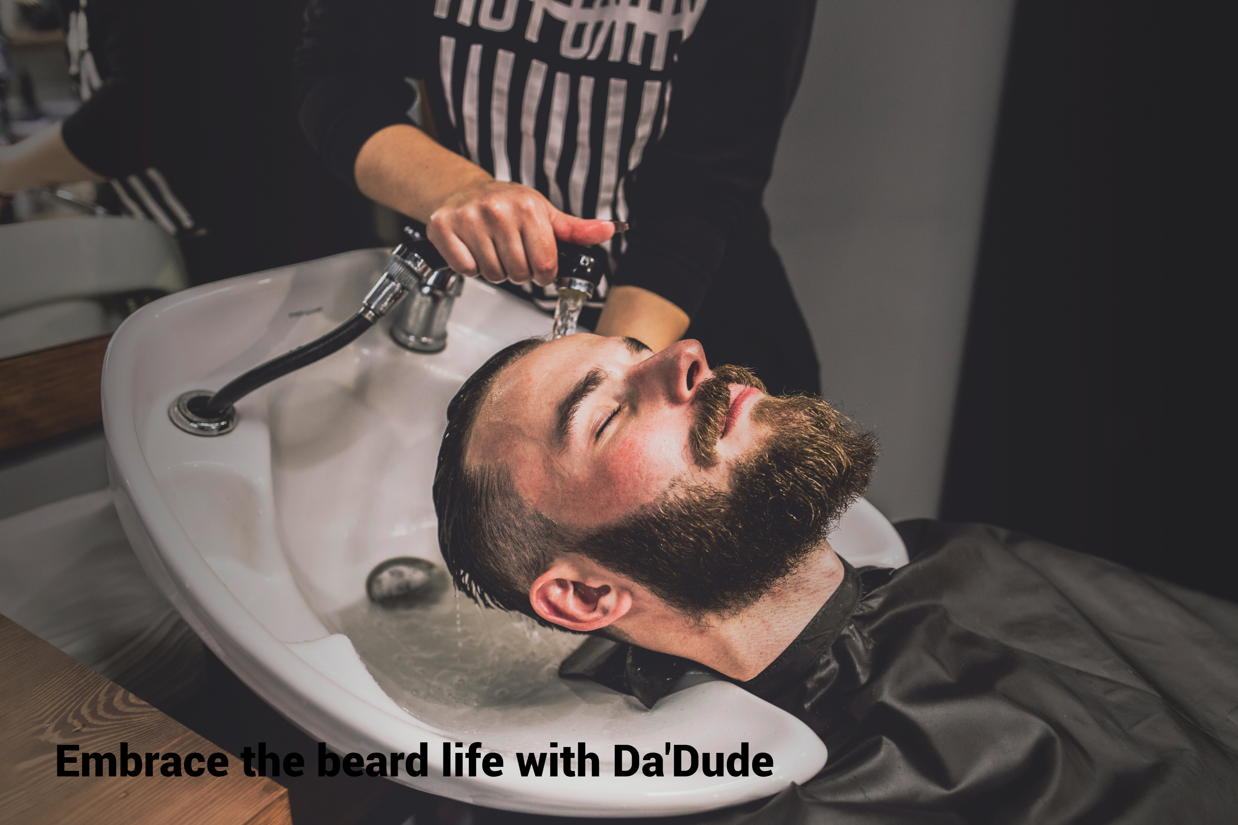 barber washing the hair of a well-bearded man in a sink