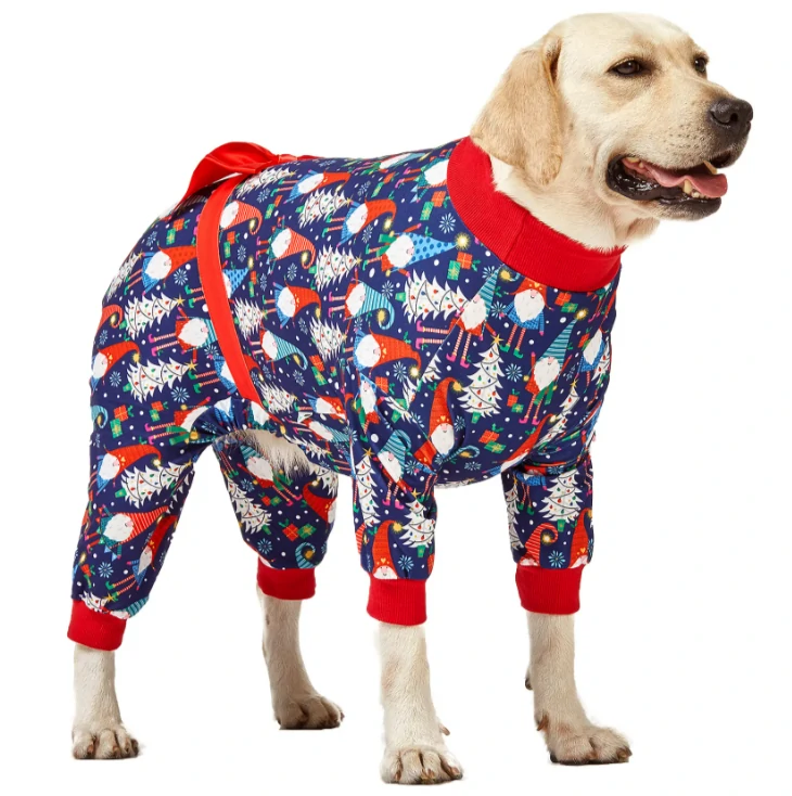 A golden retriever dressed in festive blue pajamas with red cuffs, decorated with Christmas gnomes, candy canes, and holiday trees, featuring a red bow on the back.