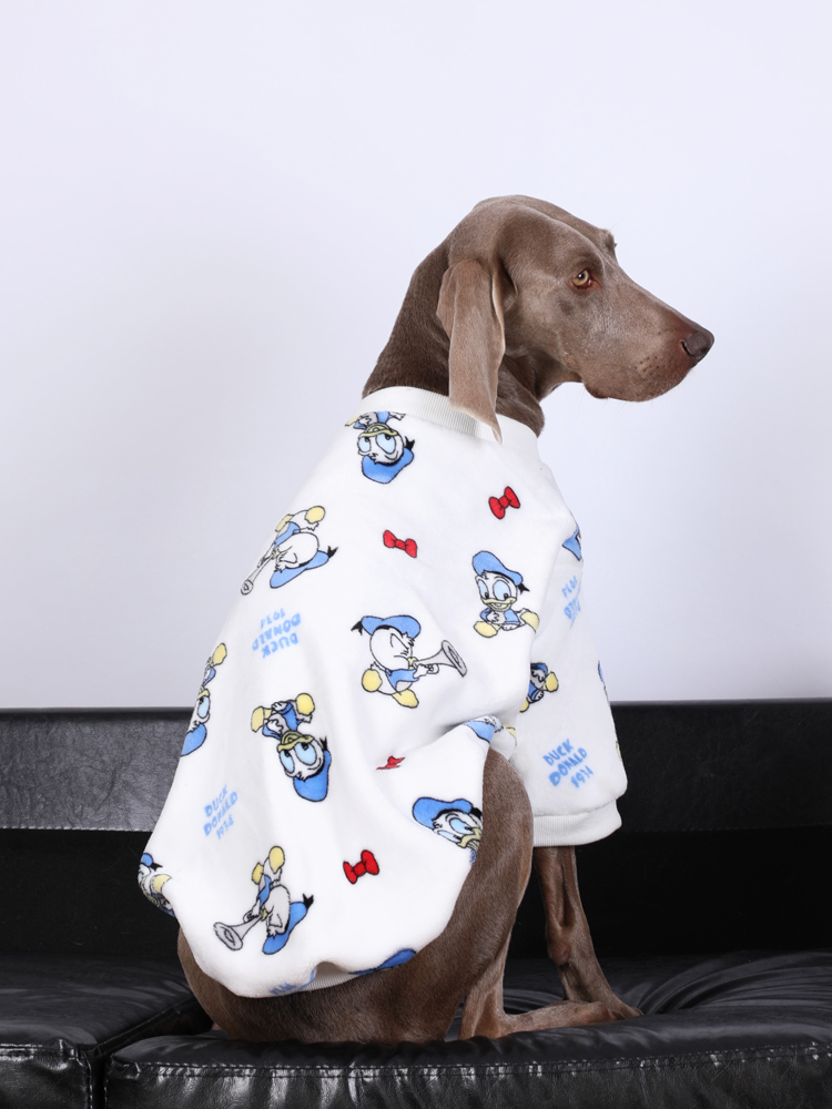 Large dog wearing a cozy white pajama with a cheerful Donald Duck pattern, sitting comfortably on a black couch.