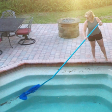 Woman holding the Pool Blaster Max Li with pool pole cleaning the pool stairs