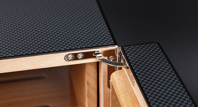 Close-up of a humidor cabinet hinge with a carbon fiber finish and precision-crafted wooden interior, showcasing durability and smooth operation for secure and stylish cigar storage.
