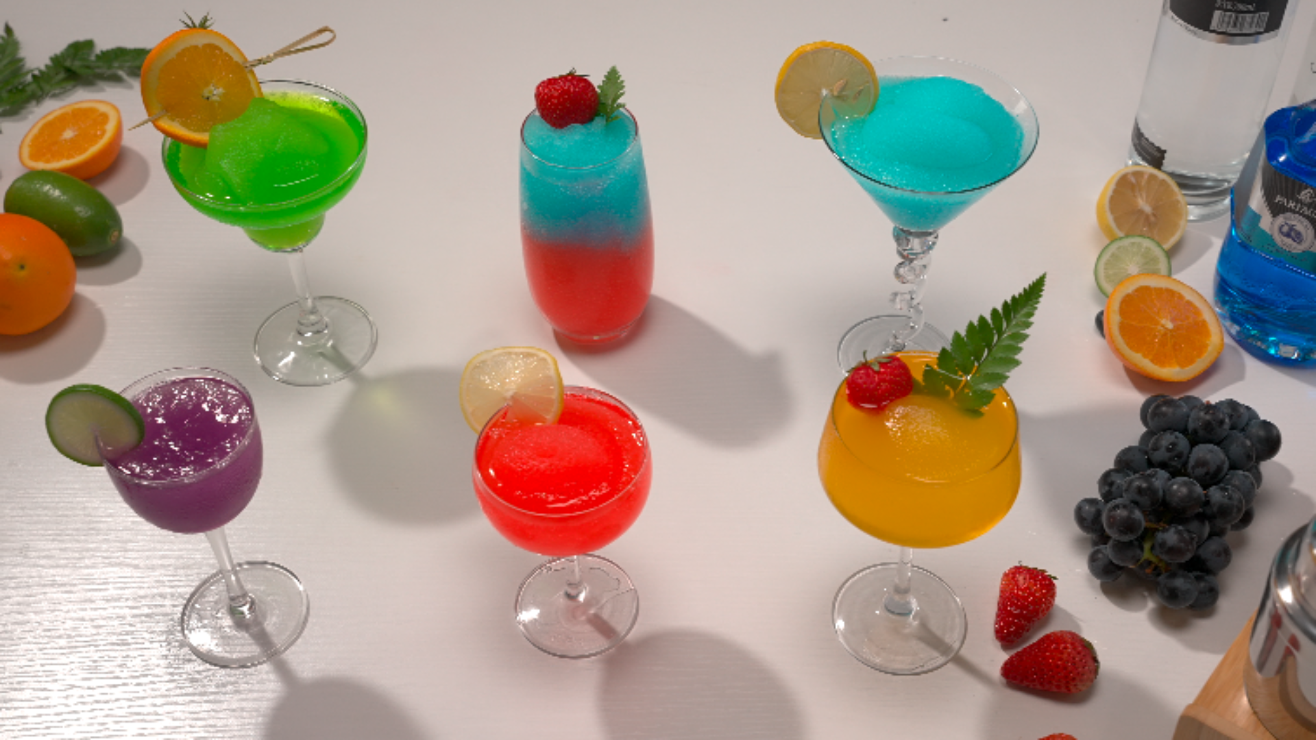 A variety of colorful slushy drinks in different glasses, showcasing vibrant flavors like green, purple, blue, orange, and red. 