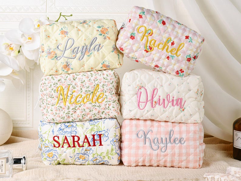 May include: Six rectangular quilted pouches with zippers, each featuring a unique floral or gingham pattern and a personalized name embroidered on the front. The names include Layla, Rachel, Nicole, Olivia, Sarah, and Kaylee in various colors.