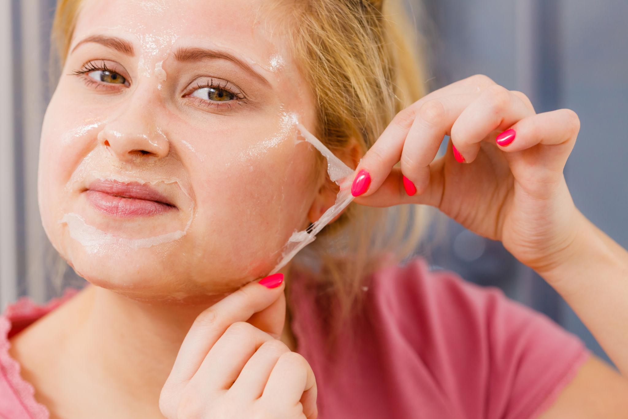 Woman peeling off gel mask from face