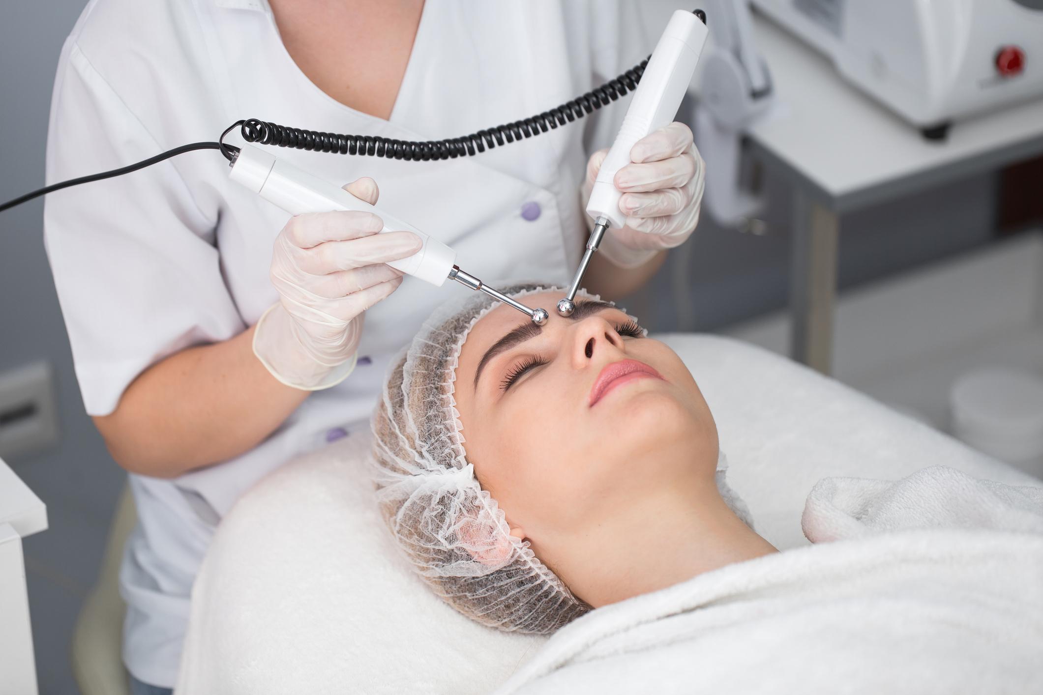 Macro close up portrait of woman having cosmetic galvanic beauty treatment in spa.Therapist applying low frequency current with electrodes on face