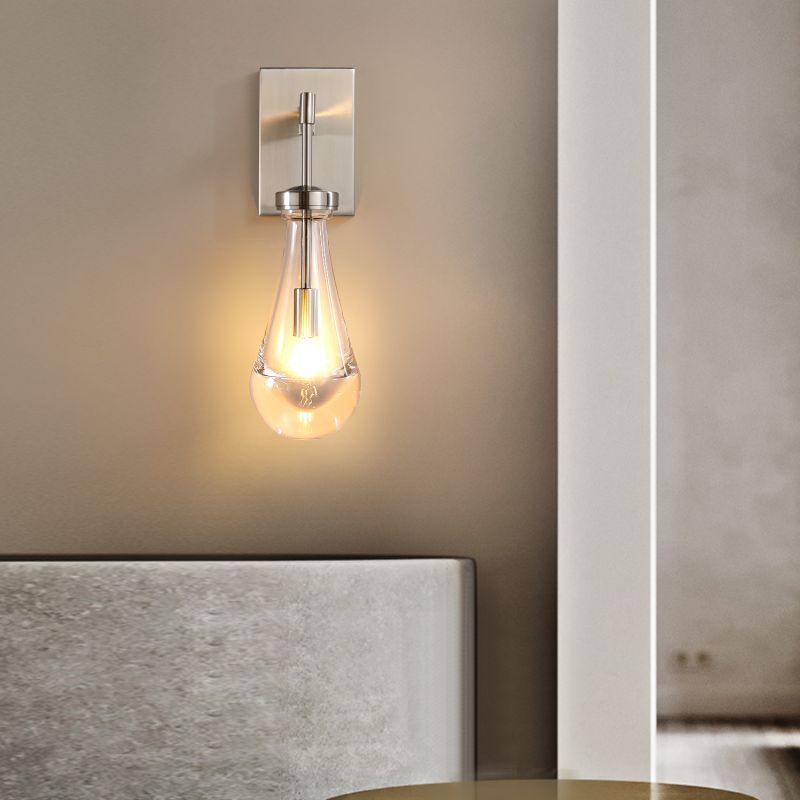 The wall sconce features blown glass drops that create a warm and inviting light in the living room. Its modern design adds a stylish touch to the decor.