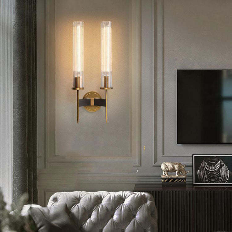 Modern dual-light wall sconce with brass and glass accents, elegantly illuminating a stylish living room interior.