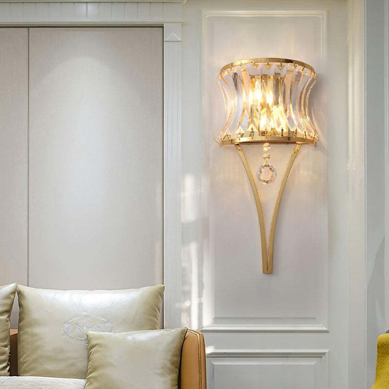 This wall sconce features arc-shaped glass panels and is mounted on the living room wall, providing soft lighting.