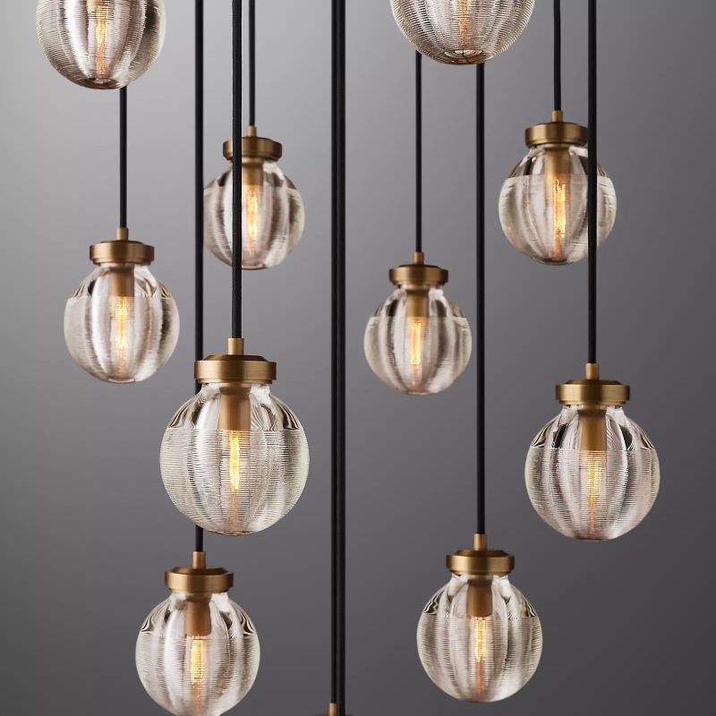 The Zylero Gold Chandelier's crystal glass balls, crafted by skilled artisans, shimmer with a golden lustre, casting a warm glow over your living room.