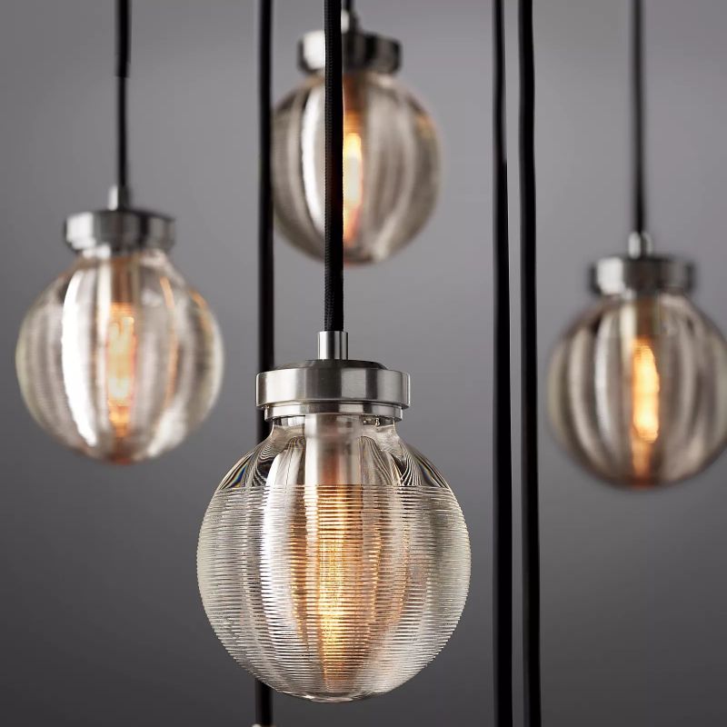 The Zylero Silver Chandelier's crystal glass elements glisten with a silver sheen, reflecting light with a cool, contemporary appeal.