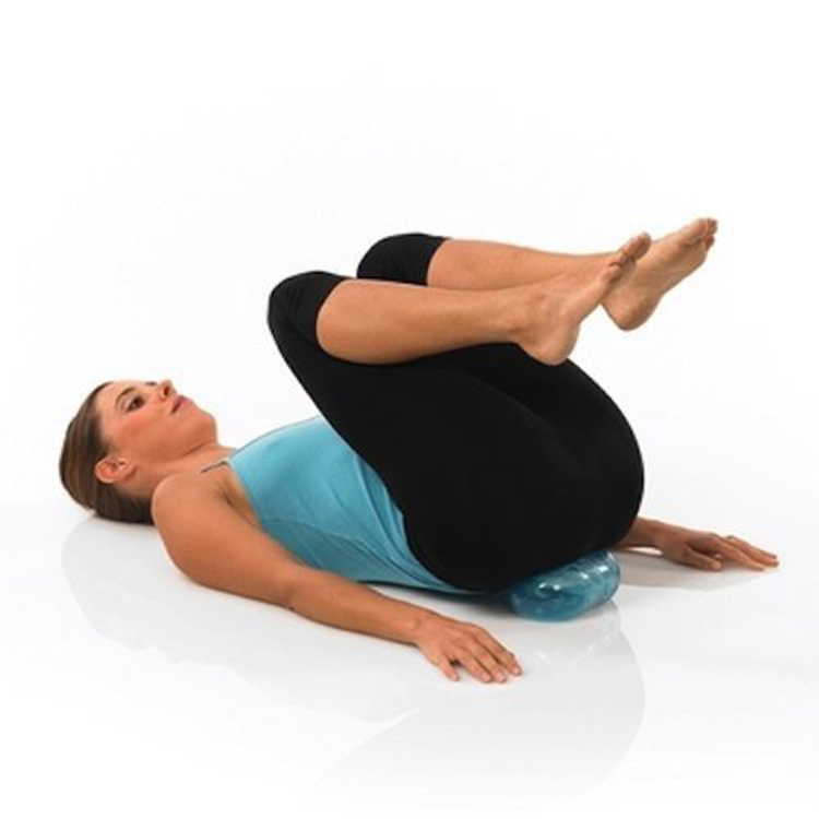 Woman performing a pelvic tilt and core exercise while lying on her back, using a Franklin Mini Roller under the pelvis to improve posture, pelvic floor awareness, core stability, and lower back mobility during Pilates or rehabilitation exercises.