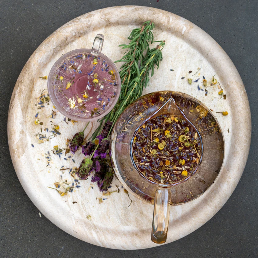 Happy Bum Co Happy Mind Tea – Overhead view of organic loose leaf herbal infusion prepared for belly or enema use, with chamomile, lavender, rosemary and wildcrafted herbs in glass cups on a stone tray, showing a calming blend for relaxation.