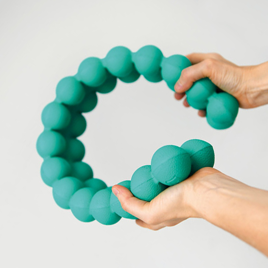 Hands bending the green Junior Spinefitter by Sissel, showing its flexible, nodule-based design for children’s posture, core stability and motor skill training.