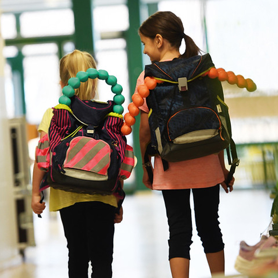 Children walking wearing backpacks fitted with the Junior Spinefitter to support posture and spinal alignment