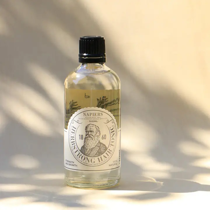 Front view of Napiers Herbstrong Hair Tonic bottle (100ml) in natural light, a herbal scalp tonic formulated with rosemary and botanical extracts to support scalp health, strengthen hair, and promote overall hair vitality.