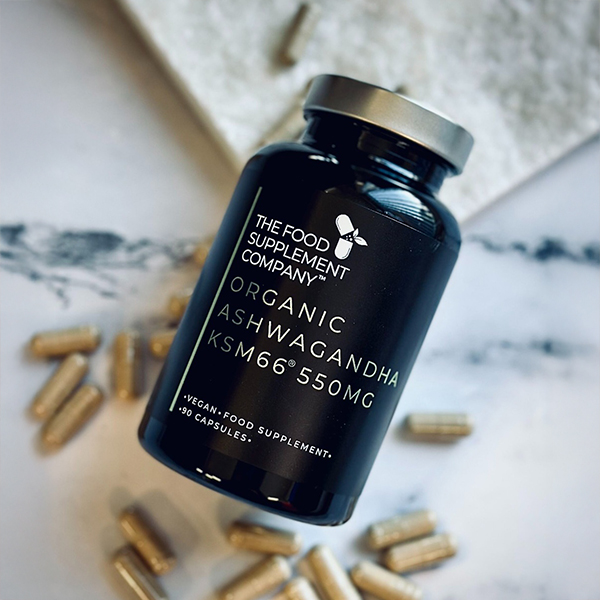 Organic Ashwagandha KSM66® 550 mg capsules by The Food Supplement Company, black vegan supplement bottle with scattered capsules on marble background, formulated to support stress management, energy levels, and mental clarity.