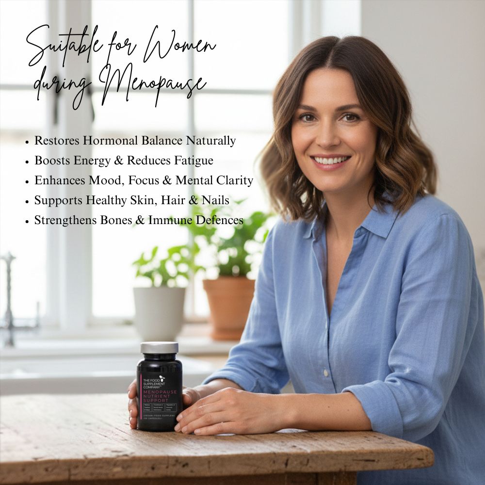 Person seated at a table holding The Food Supplement Company Menopause Nutrient Support capsules, with on-image text highlighting benefits for women during menopause, including hormonal balance, increased energy, improved mood and focus, and support for skin, hair, bones, and immunity.