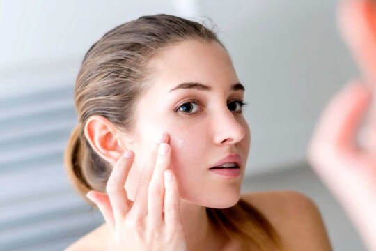 Eczema Symptoms and Treatments-StressNoMore. Woman checking her skin in the mirror and touching her cheek, illustrating skincare routines, acne concerns, blemish treatment and facial self-care.