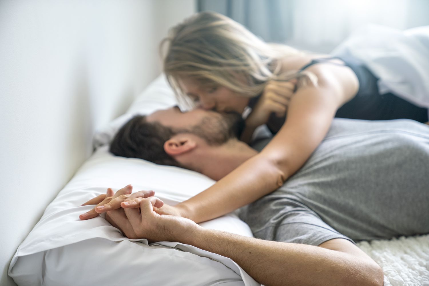Couple lying together in an intimate, affectionate moment on a bed, used to illustrate relationship concerns and challenges such as anorgasmia or difficulty reaching orgasm. Anorgasmia: What To Do If You Can’t Reach Orgasm-StressNoMore