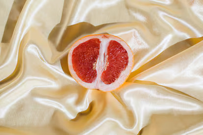 What You Don't Know About Your Intimate Flora-StressNoMore. Close-up of a halved grapefruit on satin fabric, often used as a visual metaphor in women’s health and intimacy education to represent vulva awareness, body confidence and sexual wellbeing