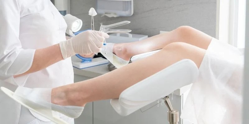 Vaginal Pessaries for Prolapse and Incontinence-StressNoMore. Healthcare professional preparing instruments for a pelvic exam while a woman lies in an examination chair, illustrating cervical screening, smear tests and routine gynaecological care.