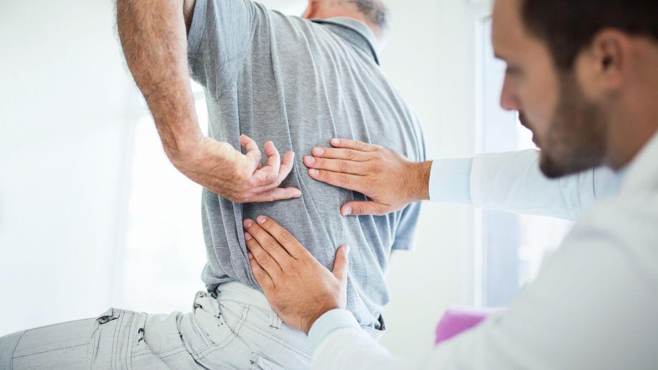Are You Damaging Your Back? - Dangerously Common Back Pain Myths Debunked-StressNoMore. “Healthcare professional assessing a man’s lower back pain by applying pressure to the area, illustrating physiotherapy, chiropractic care, muscle strain or discomfort