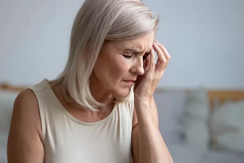 Migraines- A Guide To Everything You Need To Know-StressNoMore. Middle-aged woman holding her head in discomfort, representing symptoms such as headaches, fatigue or stress often linked to menopause or hormonal changes