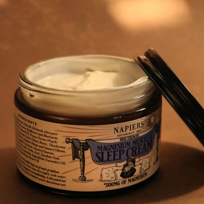 Open jar of Napiers Magnesium Muscle & Sleep Cream showing smooth white cream texture, with lid resting beside the jar, highlighting natural topical magnesium cream for muscle relaxation, skin hydration, and bedtime sleep support.