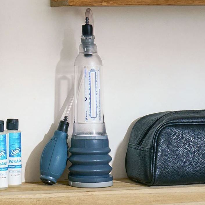 VaxAid v7 Deluxe vacuum erection device displayed on shelf with hand pump, clear pressure gauge cylinder, soft comfort base, lubricant bottles and carry case, showing a medical-grade, drug-free solution for erectile dysfunction therapy.