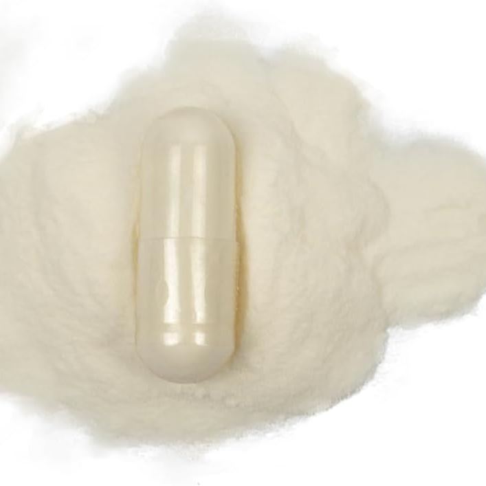Single collagen capsule displayed on a bed of fine white powder against a white background.