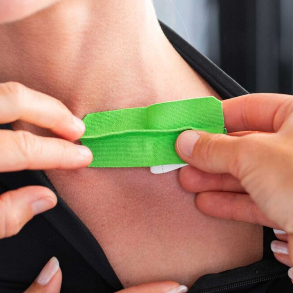 Green kinesiology tape with activation flap being applied to the neck, demonstrating deep tissue and fascia stimulation for improved circulation, lymphatic drainage, pain relief and physiotherapy support.
