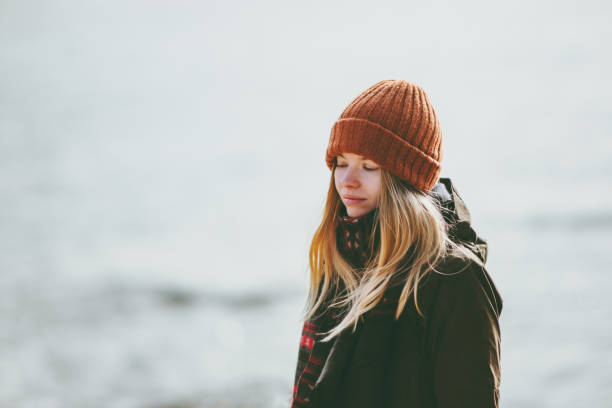 Are You Prepared for the Winter Blues?-StressNoMore. Woman wearing a warm hat and coat standing outdoors on a cold, grey day, representing seasonal mood changes and the winter blues.