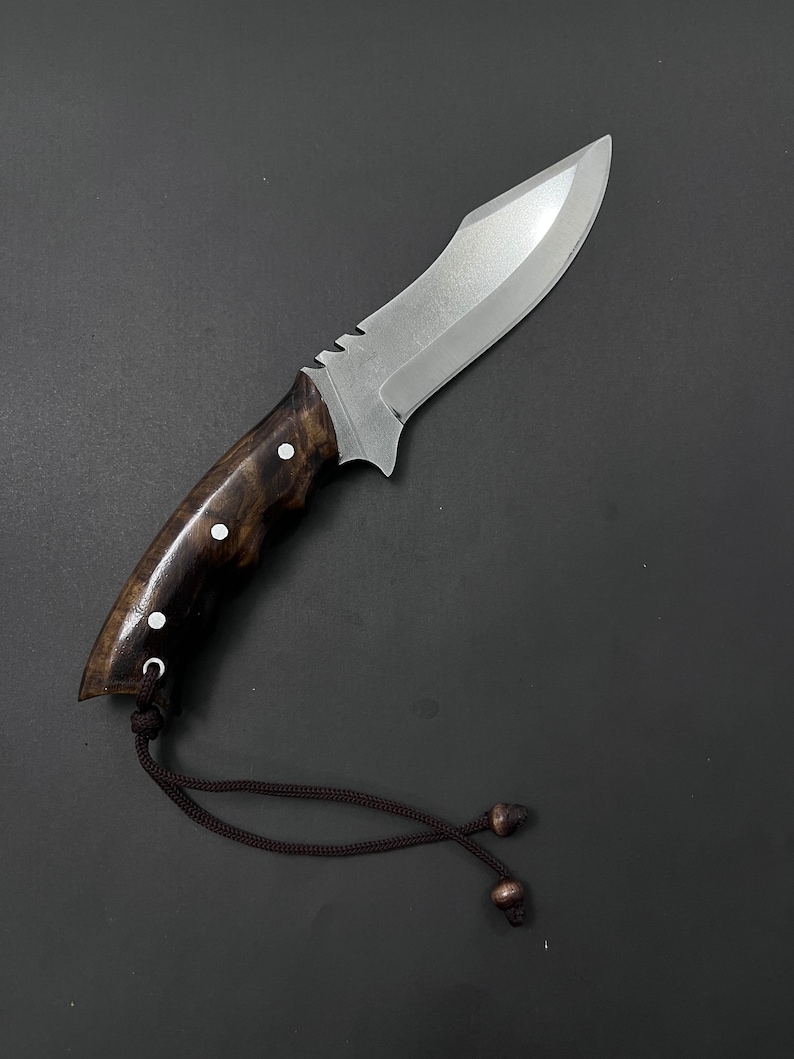 Ręcznie wykonany nóż myśliwski z pełnym trzpieniem: grawerowana stal, rękojeść z drewna orzechowego.