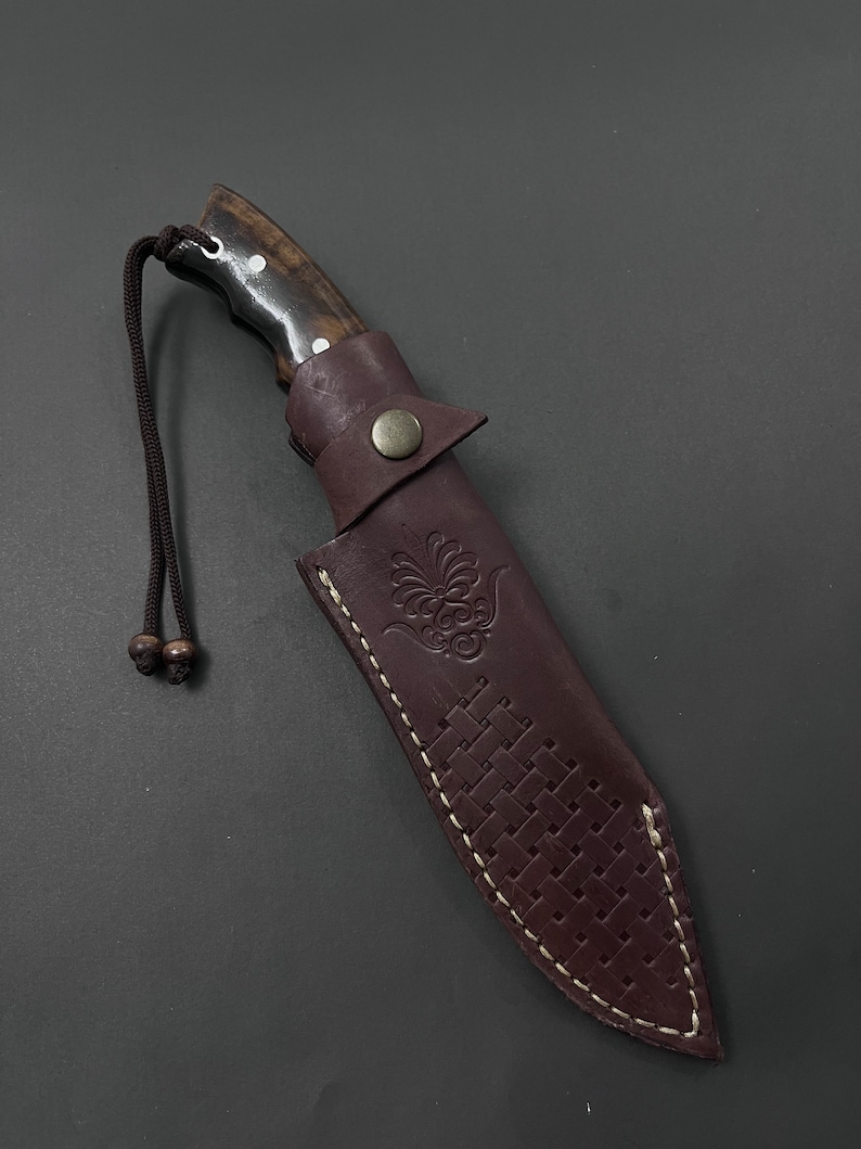 Ręcznie wykonany nóż myśliwski z pełnym trzpieniem: grawerowana stal, rękojeść z drewna orzechowego.