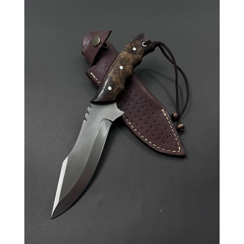 Ręcznie wykonany nóż myśliwski z pełnym trzpieniem: grawerowana stal, rękojeść z drewna orzechowego.