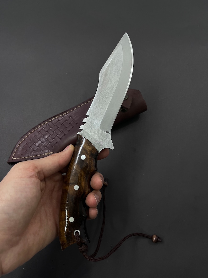 Ręcznie wykonany nóż myśliwski z pełnym trzpieniem: grawerowana stal, rękojeść z drewna orzechowego.