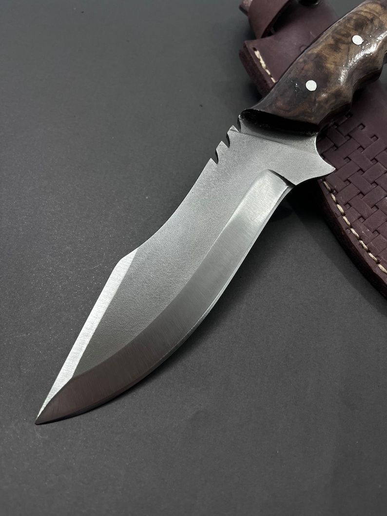 Ręcznie wykonany nóż myśliwski z pełnym trzpieniem: grawerowana stal, rękojeść z drewna orzechowego.