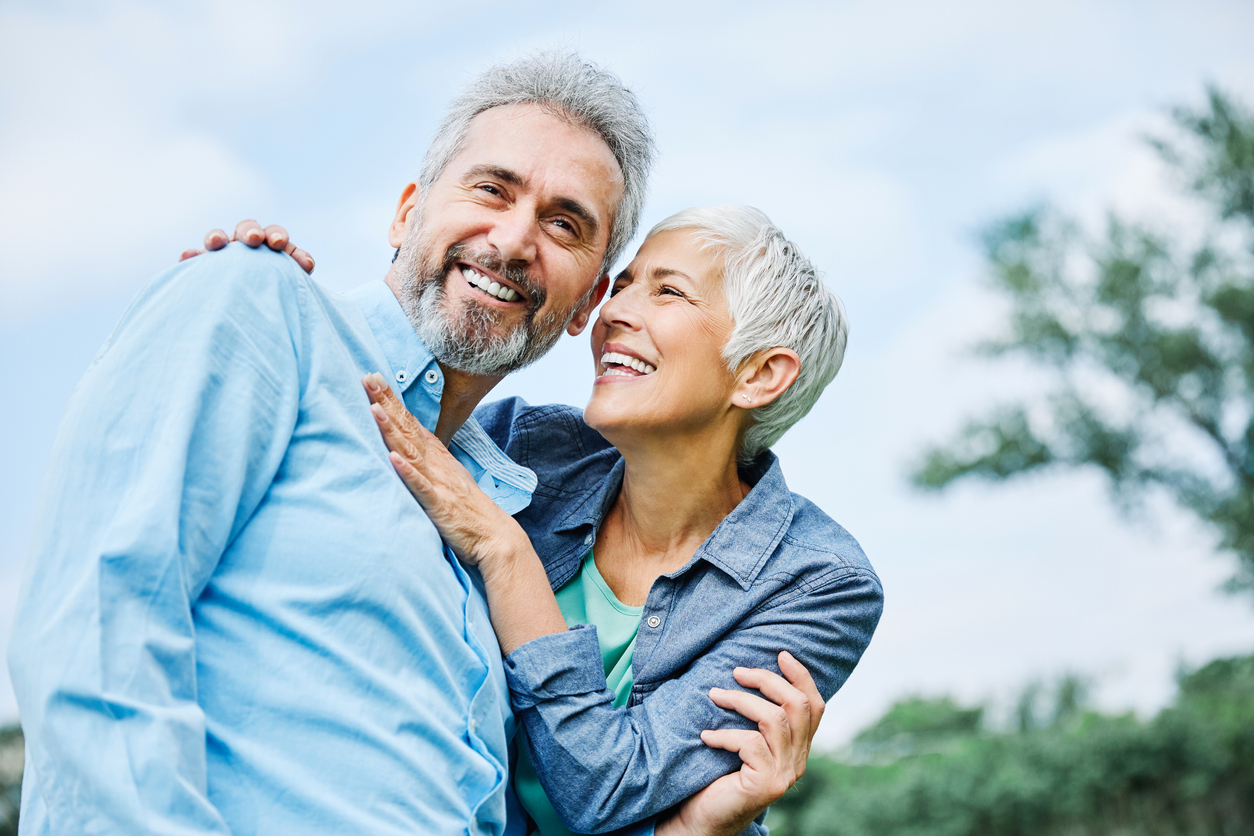 Happy older couple smiling and holding each other.