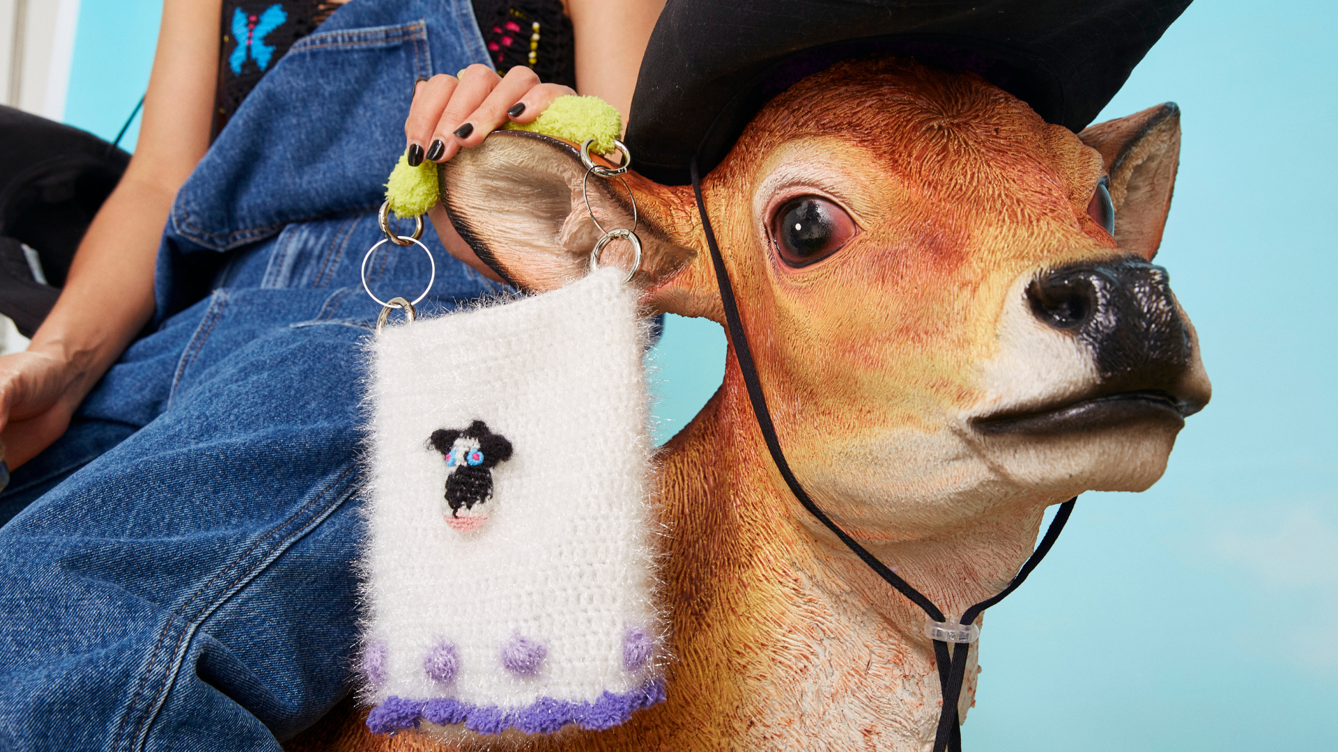 A playful and artistic still life featuring a FeekyStore handcrafted fuzzy bag held by a person in denim, perched on a vintage-style deer, perfect for soft girl and whimsical fashion lovers.